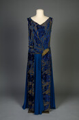 Royal blue silk chiffon evening dress with velvet floral motifs and topaz brooch at hip. Sleeveless, floor-length dress with low dropped waistline.