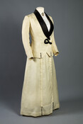 Woman's white wool walking suit with black silk satin collar and black silk-covered buttons. Comprised of a skirt and jacket.