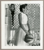 Undated photograph of American fashion designer Claire McCardell standing on a porch and holding a basket.