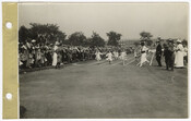 Group of children running in a foot race at a field day event in Patterson Park, Baltimore, Maryland. The children, likely girls, run on a lined course. Spectators watch from the sidelines. Buildings and trees are in the background.