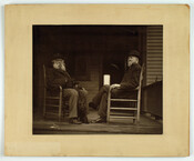 Confederate officers General Wade Hampton (1818-1902) and General Bradley T. Johnson (1829-1903) on a porch, seated in chairs facing each other, while Hampton holds a black dog.