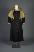 Black cotton poplin raincoat with beige caped collar and cuffs and brass buttons.