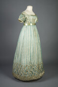 Blue and green silk gauze evening dress with feather design woven into fabric. Silk satin rouleaux trim embellishes the sleeves, bodice, and skirt hem.