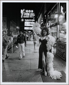 Burlesque dancer Blaze Starr (1932-2015) poses in a black dress and feather boa in front of a sign for the 408 Show Bar in Baltimore, Maryland. Referred to as "The Block," the 400 block of East Baltimore Street was known for its adult entertainment establishments.