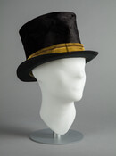 Black beaver-felt top hat with gold braid band. The inside of the hat is lined with paper and the band is light green leather. The brim is bound in silk grosgrain ribbon. This hat was worn with the Ridgely family livery (1944.76.26-28) by Tilghman Davis (b.1843). Davis was born into slavery and later as a…
