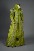 Green silk pelisse worn by Eliza Eichelberger Ridgely (1803-1867). Its distinguishing features include a silk braid cord with metal tassels, high collar, double-puffed sleeves, and silk appliqued "Vandyke"-style embellishments.