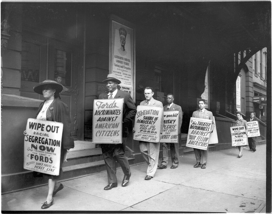 Men and women in a picket line, holding NAACP Baltimore Branch protest signs, as they march against the Jim Crow admission policy at Ford's Theatre. Mrs. Adah Killion Jenkins is at the far left; Paul Robeson second from left; and Dr. John E.T. Camper fourth from left. By 1952, Ford's Theatre (once located at 320…