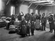 A group of immigrants who have disembarked from the North German Lloyd steamship the SS Neckar. The group is pictured in the baggage area at Pier 9 in the Locust Point area of Baltimore, Maryland.
