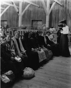 Image of women seated on a bench at the immigration station at Pier 9 in the Locust Point area of Baltimore, Maryland. The women had arrived in Baltimore via the North German Lloyd steamship the SS Neckar and are shown awaiting special examination.