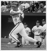 Photograph of Baltimore Orioles outfielder Jeffrey Hammonds at bat during a home game in Baltimore, Maryland. Outfielder Jack Voigt and batting coach Jerry Narron are visible in the dugout behind Hammonds.