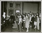 A group of student visitors stand in the gallery of the Maryland Historical Society, surrounded by framed paintings and busts.