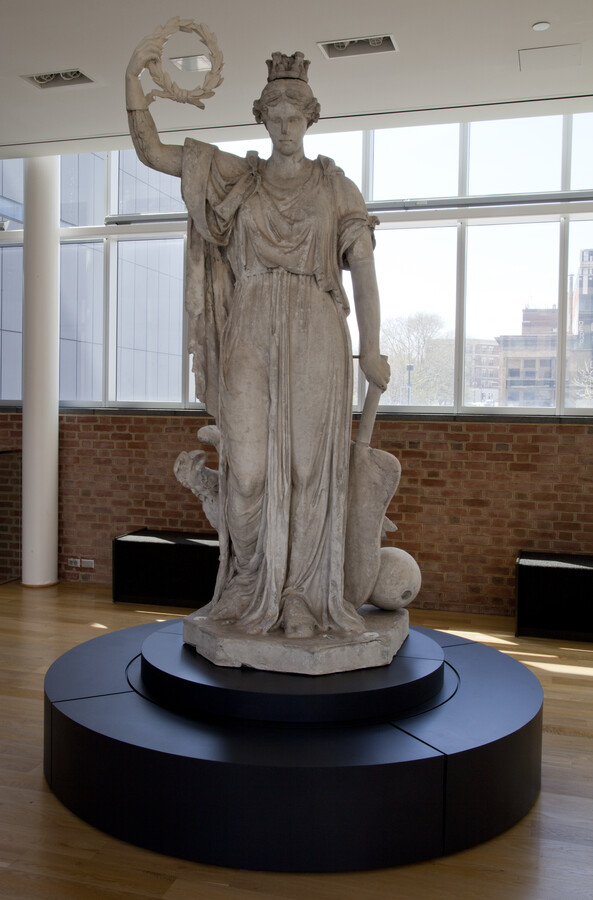 This female figure in classical dress originally stood atop Baltimore's Battle Monument which commemorated the Baltimoreans who died defending their city from the British during the War of 1812. Maximillian Godefroy, a French exile who was an architect and engineer, designed the monument and Italian scupltor, Antonio Capellano, created the statue of imported Carrera marble.…
