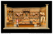 A toy butcher shop with a butcher figurine and various cuts of meat made from plaster. Also includes a cleaver, scales, cash register, saw, and more.