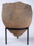 A clay food storage vessel found at Pope's Creek in Charles County, Maryland. Fired-clay food storage vessels such as this reflect the shift toward semi-permanent settlements along major rivers. The indigenous peoples who made these vessels stored a surplus of hickory nuts, chestnuts, acorns, sunflowers, and other seeds to protect them from mice, raccoons, or…