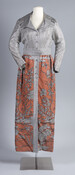 Orange and silver lurex maxi dress with belt and large fold-down collar with lapels. Worn by Llewellyn Elizabeth Lurz Albert (1912-2003). Albert was born in Baltimore on Federal Street and baptized at St. James the Less Church. Her mother was born in Westphalia, Germany, and her father, although born in Baltimore, was a first generation…