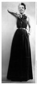 Full body portrait of American fashion designer Claire McCardell in a dark dress sliding open a glass panel.