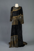 Black and gold velvet tea gown with draped neckline and puffed, full-length sleeves. Decorated with silk-screened metallic Grecian-style motifs.