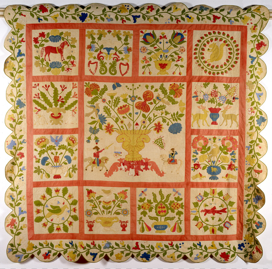 A Baltimore album quilt by Rachel Meyer Walter, a Bavarian immigrant who came to America in 1839. The quilt features plain and printed cottons, wool, and silk embroidery; it has scalloped edges, a center square depicting a large urn full of flowers, and other floral and leaf imagery throughout.