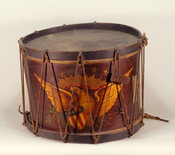 A drum from the American Civil War decorated with a painted eagle. The drum bears a silver plaque that reads: "Presented to James W. Sank, by the officers and men of Camp A Purnell Legion Md. Vols. May 1863." Sank had been a union drummer boy; he survived the war and returned to Baltimore to…