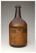 Brown glass bottle, with hand-drawn written labels. Left side. Two cartoons pasted on each side.