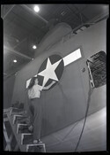 An employee of the Glenn L. Martin Company painting a star design on the side of an airplane.