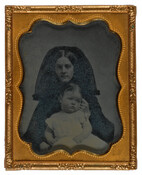 A cased ambrotype portrait of 14-month-old Louisa R. Coolidge and a woman presumed to be her mother. The child is dressed in a white dress and sits in the lap of the woman who is wearing a black dress with black veil.