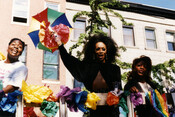 Three participants with paper flowers at the Pride Parade in Baltimore, Maryland. The first Baltimore Pride was held in 1975 and consisted of activists coming together in a peaceful demonstration. Throughout the decades, the Pride celebration has taken place throughout much of the city, primarily in the Mt. Vernon neighborhood and Druid Hill Park.