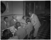 Charles Law and company seated at a booth in an unidentified restaurant during social hour. Charles Law was a prominent funeral director whose funeral home was located at 802 West Madison Avenue in Baltimore, Maryland.