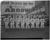 The Elite Giants, a Negro League baseball team from Baltimore, Maryland, posed in front of a scoreboard with an advertisement celebrating the 200th anniversary of Arrow Beer.