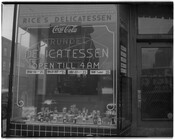 The storefront window of Rice's Delicatessen. A Coca-Cola advertisement hangs above neon lighting that reads, "Arundel delicatessen open till 4AM."