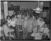 Group of men and women in an office, likely at the Afro-American newspaper building in Baltimore, Maryland. Office doors contain nameplates, "Mr. H.H. Murphy" and "Mr. B.A. Murphy."