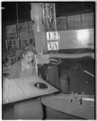 Woman working at a factory machine, possibly as a World War II defense worker.