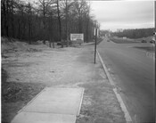 View of a sidewalk ending on Northern Parkway in Baltimore, Maryland. A sign in the background reads, "Meridene Drive...Northern Parkway..."