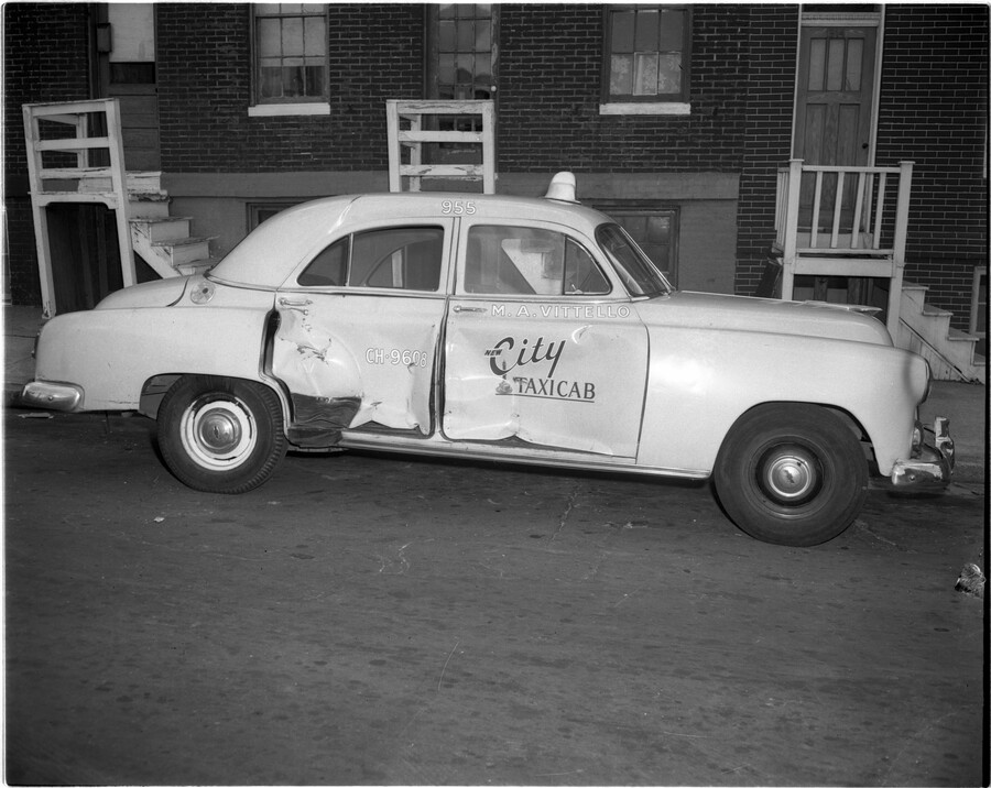 View of a damaged city taxicab parked in front of a group of row houses on Amity Street in Baltimore, Maryland.