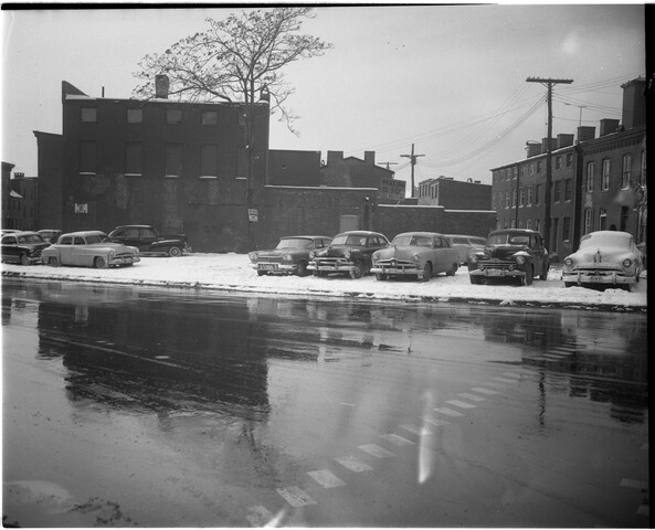 Parking lot with automobiles in snow — circa 1957-01