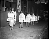 A line of protesters outside of Ford's Theatre in Baltimore protesting Ford's Jim Crow admission policy. Signs worn by the protesters include statements such as "Segregation cheats me of human dignity;" "This theatre discriminates;" This theatre! denies us the democracy we fought for;" and Anti-Semitism is kin to Jim-Crowism / We oppose both!"