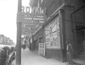 Exterior view of the Royal Theatre located at 1329 Pennsylvania Avenue in Baltimore, Maryland. An unidentified man stands in front of the theatre as several people walk towards it.