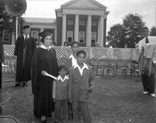 Juanita Jackson Mitchell at her graduation from University of Maryland School of Law in College Park, Maryland. Mitchell is surrounded by sons Clarence M. Mitchell III, Keiffer Mitchell, and Michael Bowen Mitchell. Several unidentified people are in the background along with a large building.