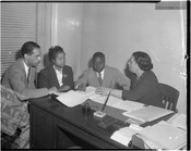 Lillie May Carroll Jackson (far right) in a meeting with Gloster B. Current (second from right) and two unidentified people. The group is seated at a desk with several documents in front of them.
