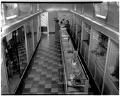 Interior view of The Charm Centre, a clothing and accessories store, with a customer and employee standing at the counter. The store was located at 1811 Pennsylvania Avenue in Baltimore, Maryland.