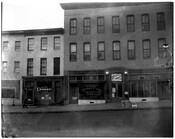 Street scene of businesses on 1430-1434 Pennsylvania Avenue in Baltimore, Maryland. From left to right is Charlie Hom Laundry; West Baltimore District Office Supreme Liberty Life Insurance Company of Chicago, Illinois; a sign for "Juke Box Hop Dancing;" J. Arnell Frisby Real State Insurance Accounting and Auditing; and a pedestrian on the sidewalk.