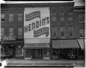 An exterior view of Jay Dee Shoes and Hendin's Hollywood and New York Fashions store located, respectively, at 1727 and 1725 Pennsylvania Avenue in Baltimore, Maryland. Hendin's was owned by Walter Hendin (1920-1970) and his brother. The store carried well-tailored, quality high fashion apparel and eventually moved to Mondawmin Mall in West Baltimore.