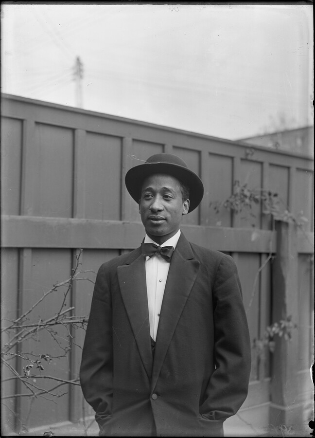Portrait of a man in formal attire, including a bowler hat, suit, and bow tie.