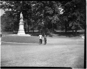 View of two young boys walking in Druid Hill Park, Baltimore, Maryland, past a statue of Italian explorer Christopher Columbus.