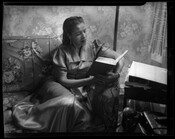Verda Mae Freeman Welcome (1907-1990) seated on a couch reading a book. Welcome was a public school teacher, civil rights activist, and one of the first Black women to be elected to a state senate in the United States.