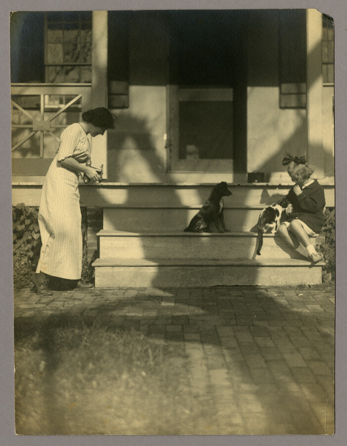 Ruth Hayden (Wanzer) and Anna "Nan" Bradford Hayden (Agle), daughters of the Baltimore, Maryland, photographer Emily Spencer Hayden, with a cat and dog on the front steps of their house in Catonsville, Maryland. Verso transcription: Ruth and Nan Hayden - Side door at Catonsville