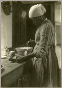 View of Eliza Benson (1836-1921) holding a mixing bowl in the kitchen of Baltimore, Maryland, photographer Emily Spencer Hayden. With the deaths of Emily's parents A. C. Bradford "Braddie" Harrison Spencer (1841–1882) and Edward Spencer (1834–1883) in the early 1880s, care of the younger Spencer children was left to Benson. A formerly enslaved African American,…
