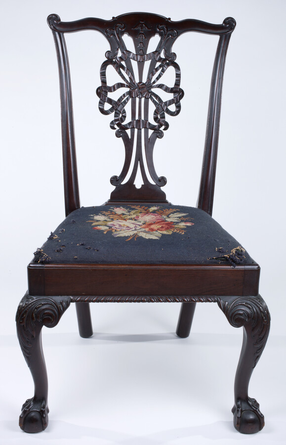 A side chair known as "The Ribbon Chair," created for the Jamestown Exhibition of 1907 by the Potthast Furniture Company. Features a needlepoint cushion (not original) made by Marie Potthast in the 1930s.