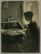 Portrait of a woman writing while seated at a desk.
