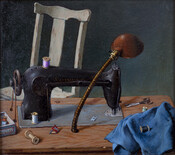 Still-life scene of a small, black sewing machine on a wooden table with a lamp, spools of thread, and blue fabric. White wooden chair and gray wall in background.